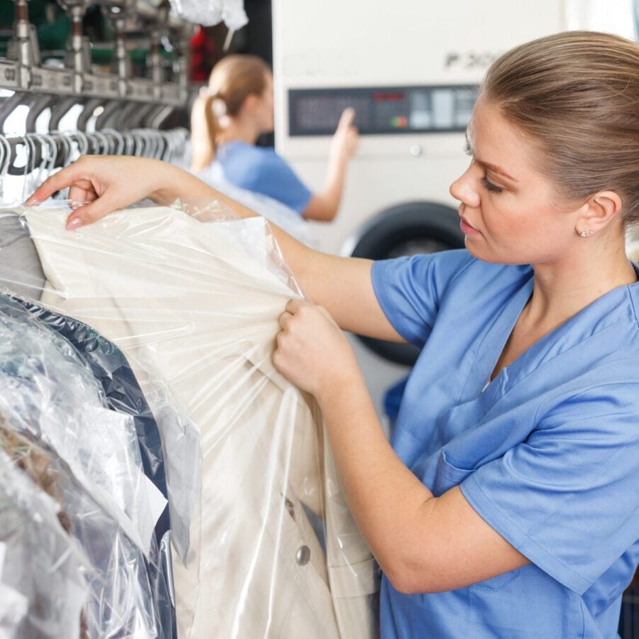 worker of laundry inspecting clothes after dry cleaning, satisfied with result